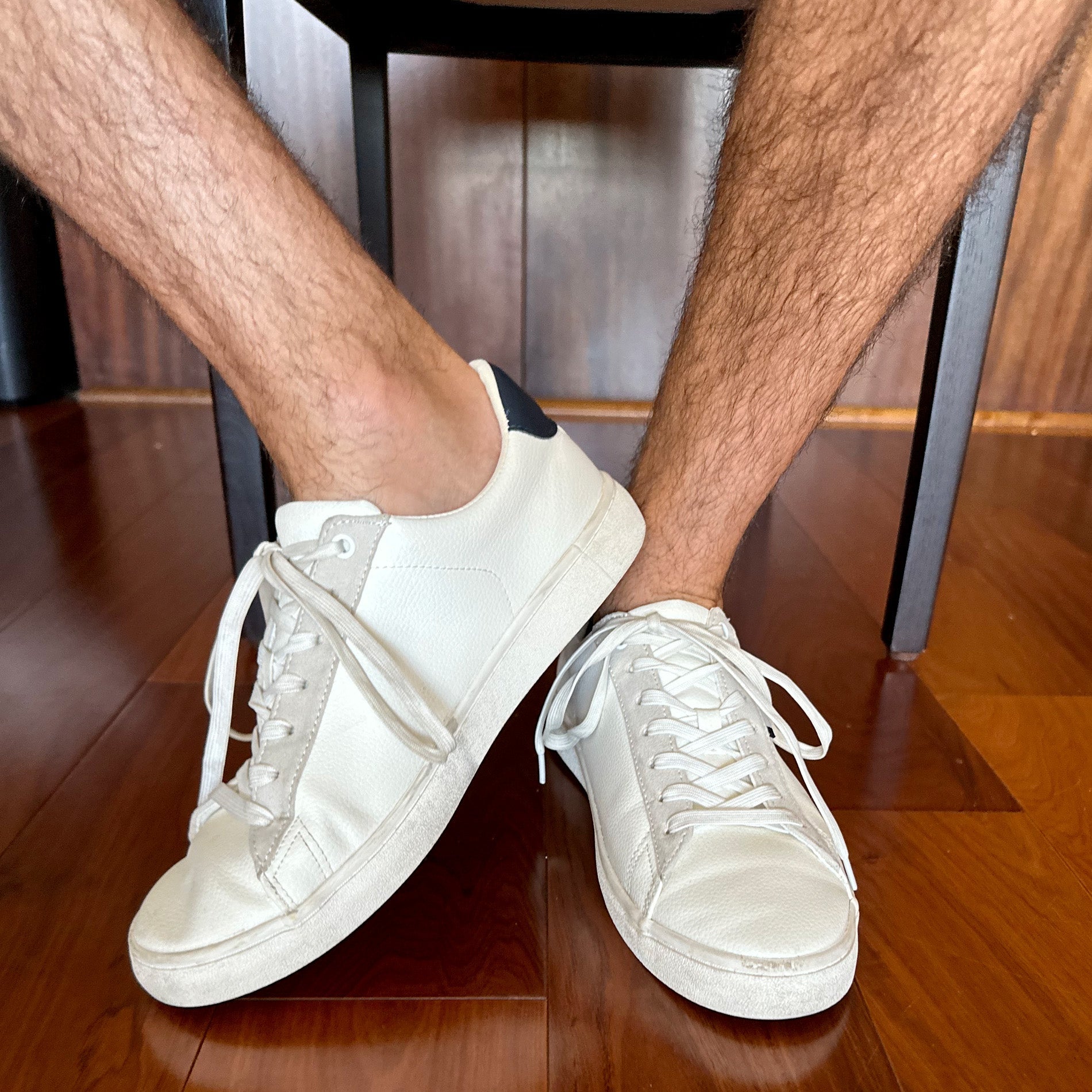 Photo of man's legs and feet wearing sneakers, with socks not visible