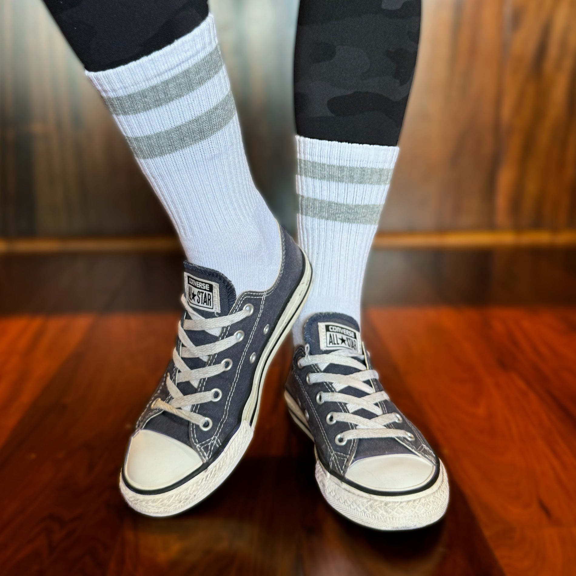 Photo of a woman's legs and feet wearing Chuck Taylor sneakers, with Skinnys Tubes crew socks